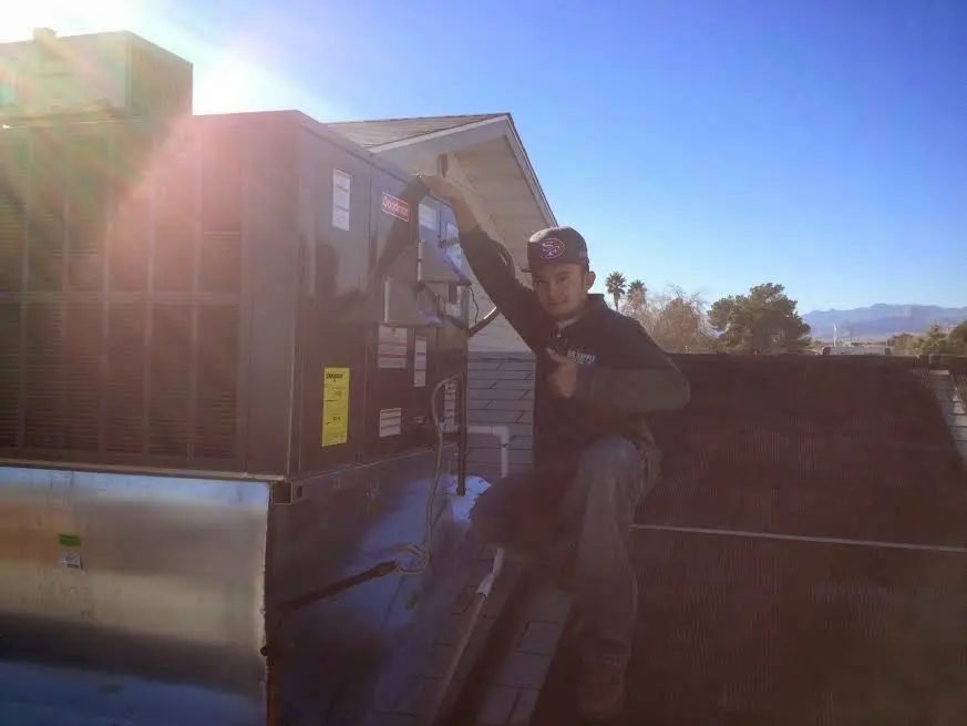 HVAC technician performing AC Tune-Up on a rooftop unit in Clinton